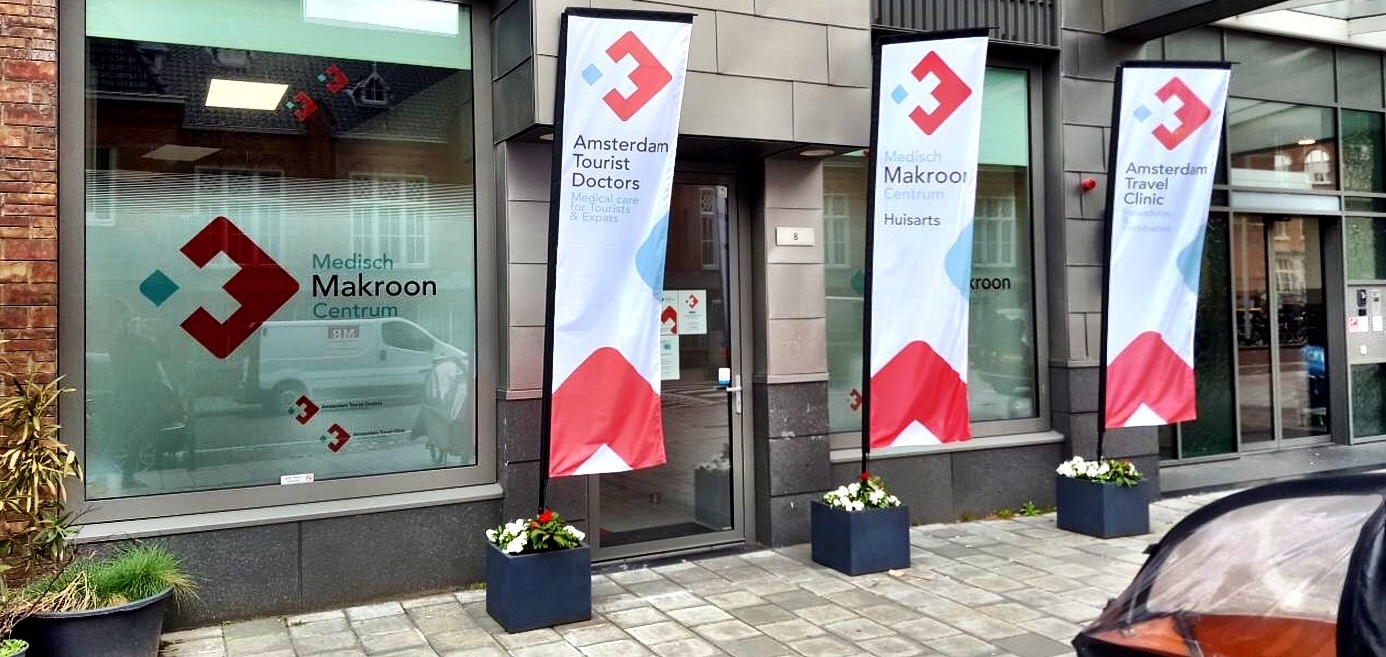 Makroon Medisch Centrum aan de Nieuwe Passeerdersstraat 8 te Amsterdam, met vlaggen van Huisartsenpraktijk de Makroon, Amsterdam Tourist Doctors en Amsterdam Travel Clinic